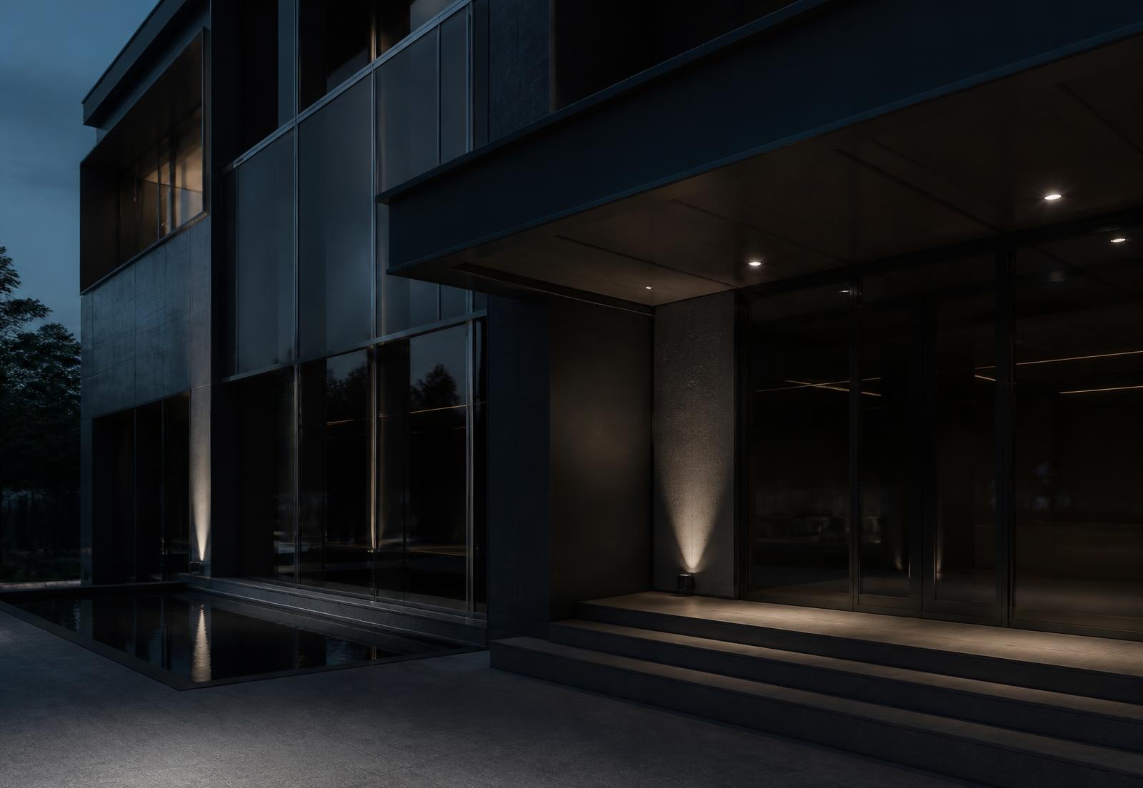 Façade contemporaine en verre fumé et acier éclairée par une lumière rasante