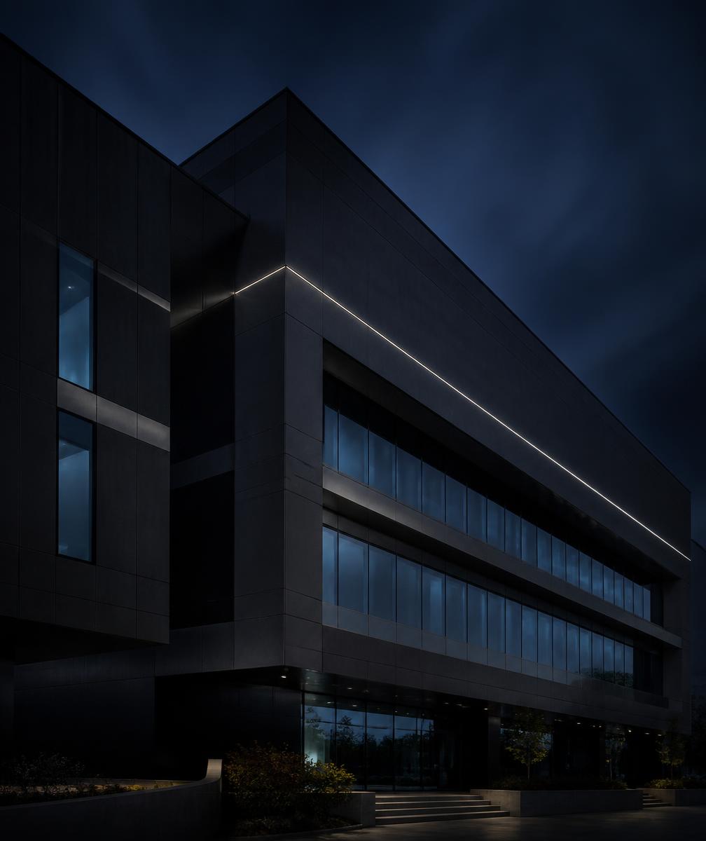 Façade d'architecture contemporaine sombre en verre fumé et acier, éclairée par une lumière rasante